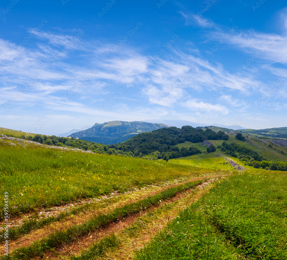 ground road among green mountain under cloudy sky at summer day ground road among green mountain under cloudy sky at summer day