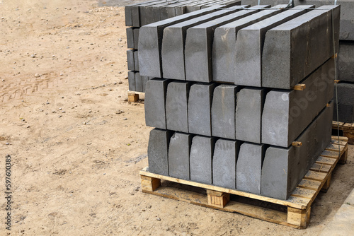 Warehouse of cement pressed materials on wooden pallets. Large pile of grey slabs and curbs for work at construction site in street. Repair walkway pavement laying. Stack of concrete paving stones.