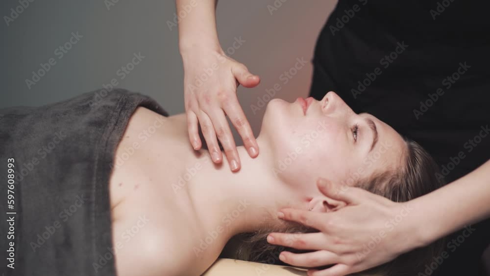 Attractive young woman in spa salon. A masseuse massages a woman's face and neck. Relaxation, stress relief body in the wellness center. Attractive young woman in spa salon. A masseuse massages a woman's face and neck. Relaxation, stress relief body in the wellness center.