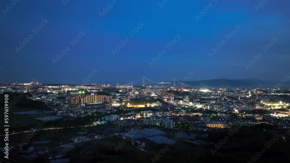 Aerial approach to glowing city and lit suspension bridge in twilight Aerial approach to glowing city and lit suspension bridge in twilight