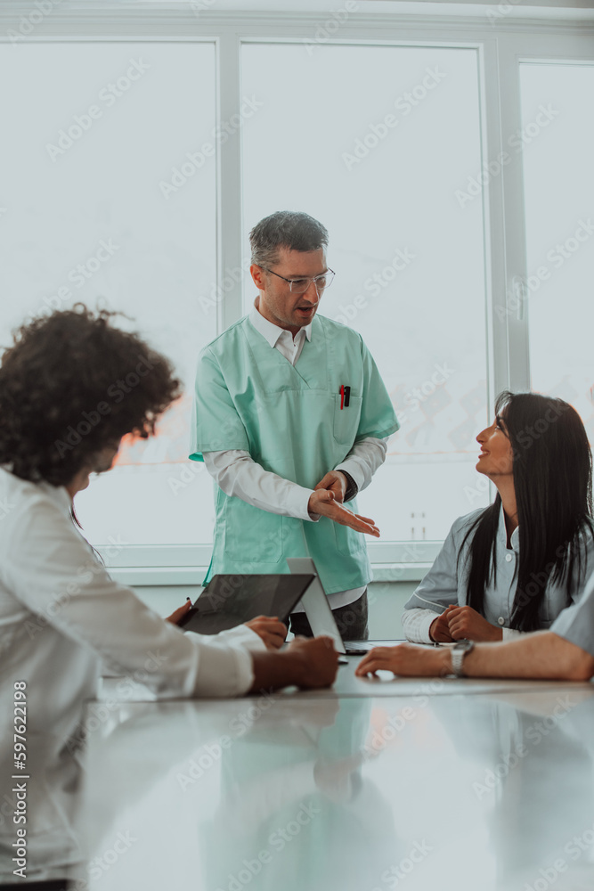 Obraz premium A group of multiethnic medical professionals including doctors, surgeons, and nurses are gathered in a hospital setting discussing patient care and using modern technology to address challenges in