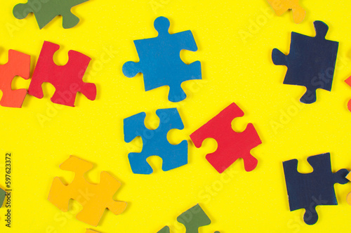 Colorful jigsaw puzzle pieces on yellow background. Top view.