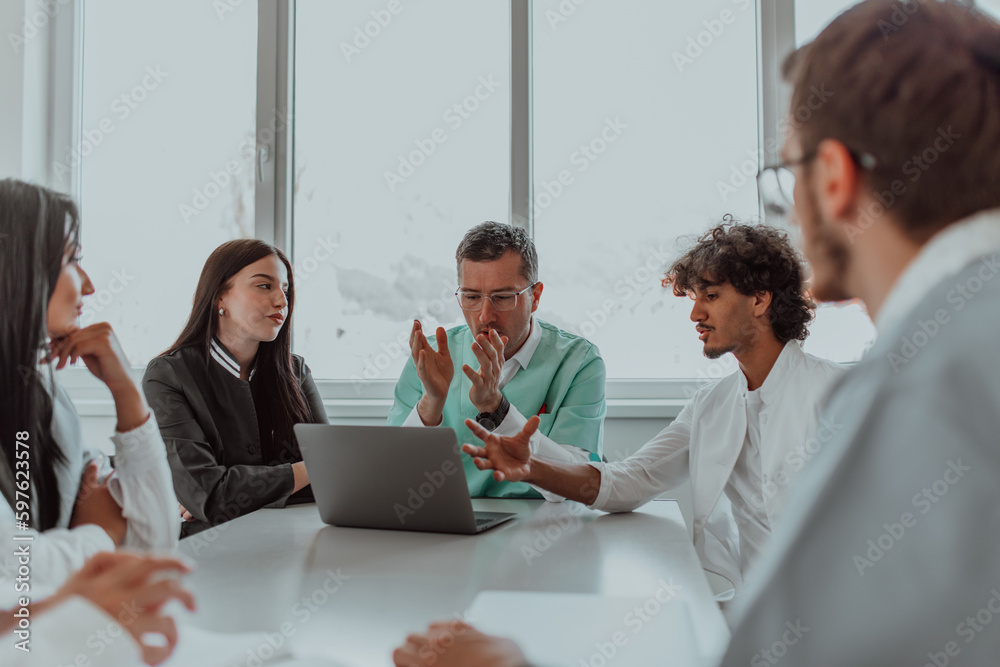 A group of multiethnic medical professionals including doctors, surgeons, and nurses are gathered in a hospital setting discussing patient care and using modern technology to address challenges in