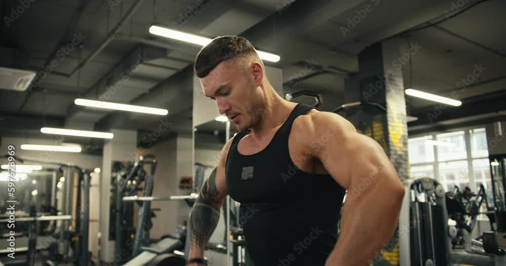 Close-up of an athletic man doing unusual barbell curls to gain muscle mass. Portrait of caucasian sportsman lifting weights in the gym Close-up of an athletic man doing unusual barbell curls to gain muscle mass. Portrait of caucasian sportsman lifting weights in the gym