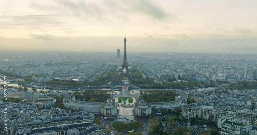 Beautiful view of famous Eiffel Tower in France with magical morning cloud and fog. Wide establishing aerial drone fly over seine river in paris city center, best travel destination landmark in Europe