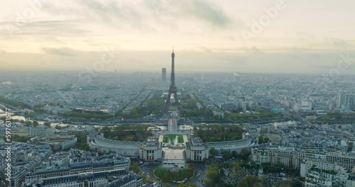 Beautiful view of famous Eiffel Tower in France with magical morning cloud and fog. Wide establishing aerial drone fly over seine river in paris city center, best travel destination landmark in Europe