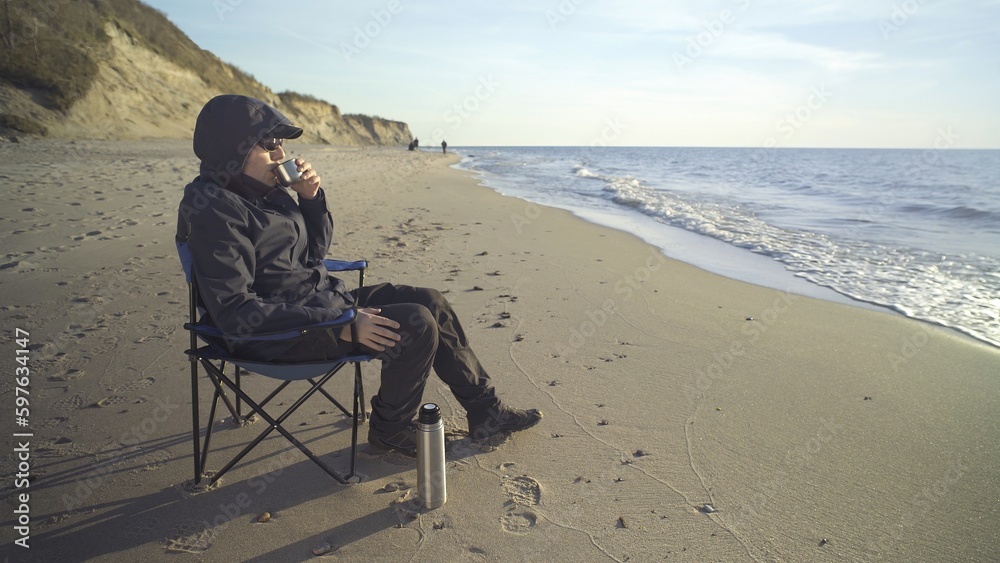 rest on the shore, a man on a chair with a thermos of tea