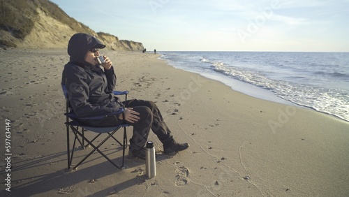 rest on the shore, a man on a chair with a thermos of tea © vadimborkin