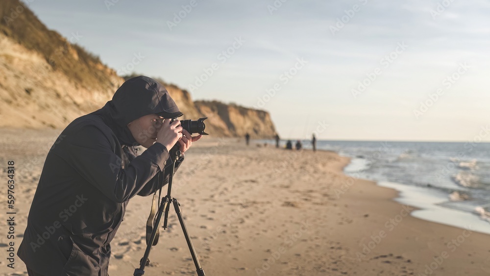 photographer on the background of sandy cliffs on the seashore