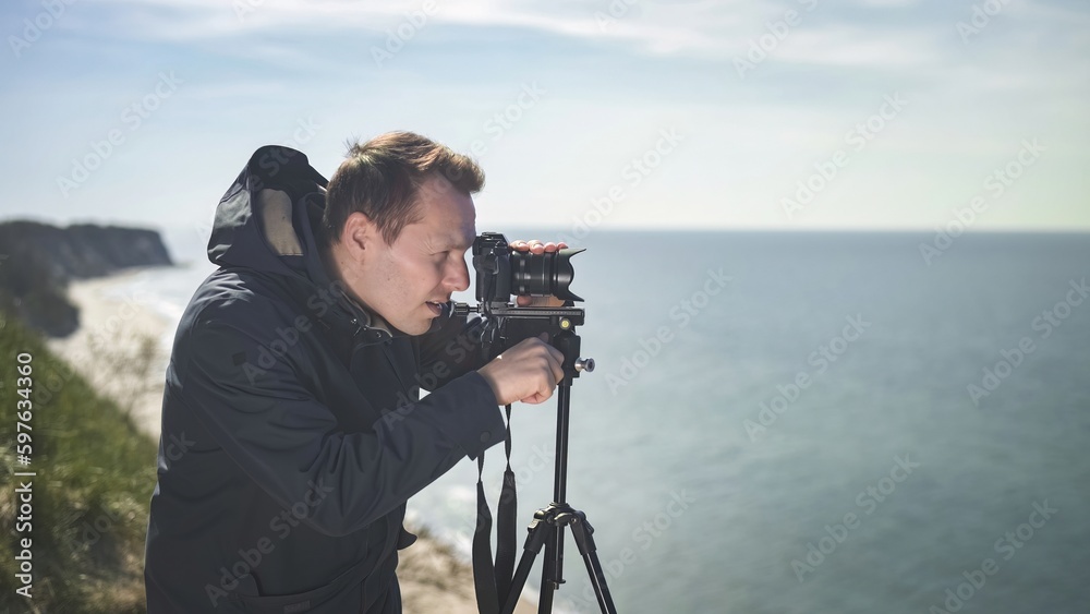 photographer with a tripod on a cliff against the background of the sea