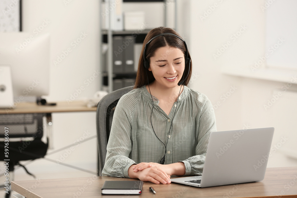 Hotline operator with headset working on laptop in office Hotline operator with headset working on laptop in office