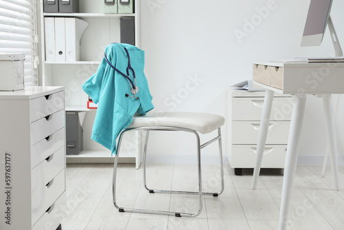 Turquoise medical uniform and stethoscope hanging on chair in clinic © New Africa