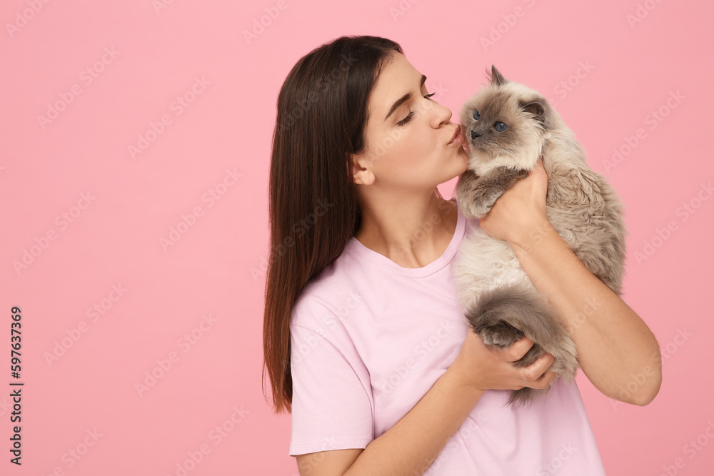 Woman kissing her cute cat on pink background, space for text Woman kissing her cute cat on pink background, space for text