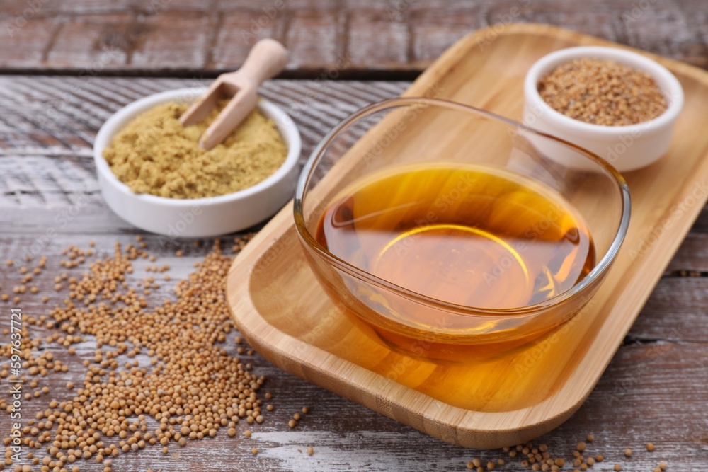 Bowl of natural oil, mustard seeds and powder on wooden table, closeup Bowl of natural oil, mustard seeds and powder on wooden table, closeup