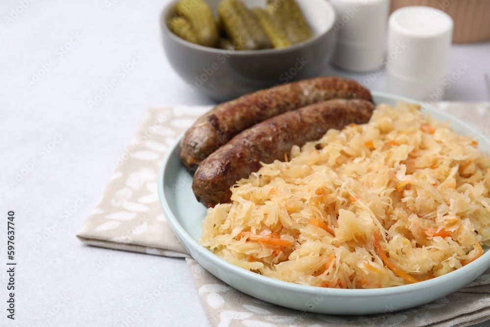 Plate with sauerkraut and sausages on light grey table, closeup. Space for text Plate with sauerkraut and sausages on light grey table, closeup. Space for text
