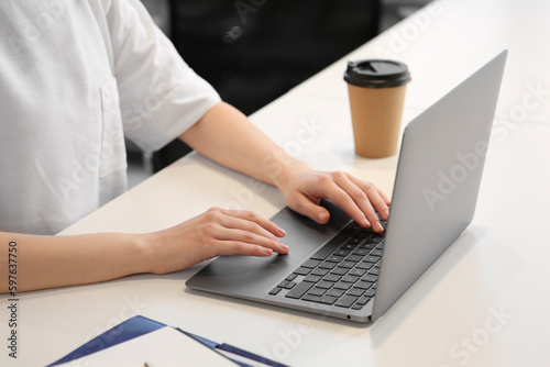 Woman working with laptop at white desk  closeup