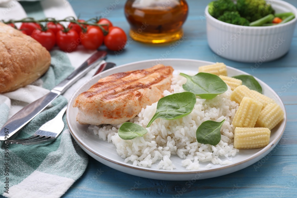 Grilled chicken breast and rice served with vegetables on light blue wooden table