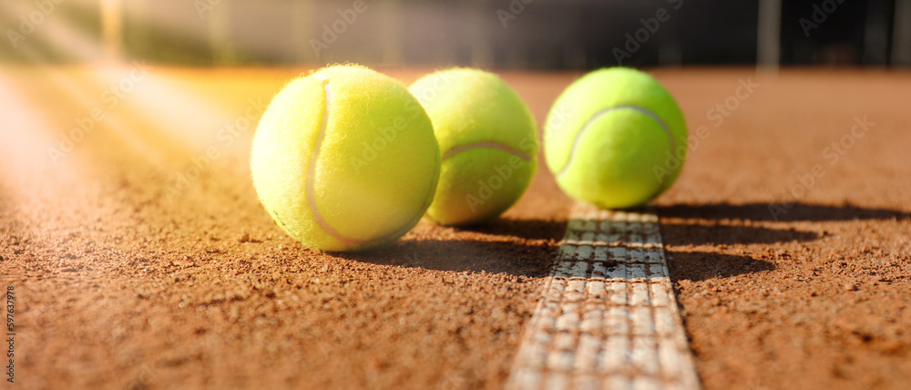 Bright yellow tennis balls on clay court, banner design