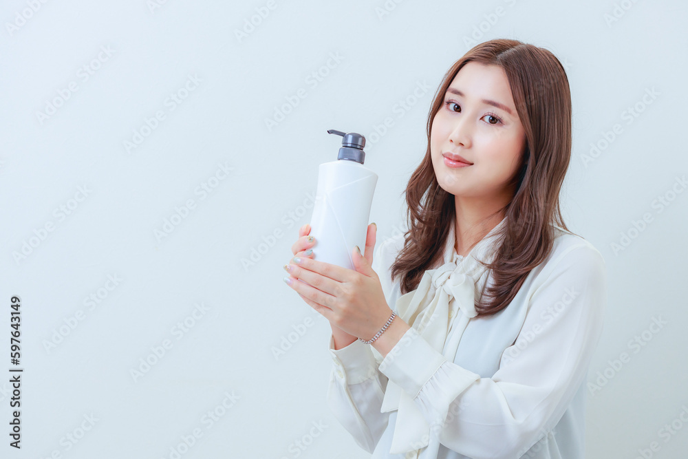 白色のシャンプーを持ったカメラ目線の女性 白色のシャンプーを持ったカメラ目線の女性