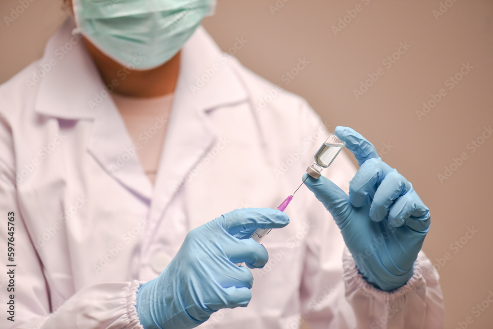 A doctor is using a syringe to give a vaccine to a visitor at the hospital. A doctor is using a syringe to give a vaccine to a visitor at the hospital.