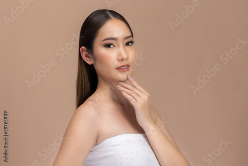 Beautiful Asian woman touching eyebrow smile with clean and fresh skin Happiness with positive emotional,isolated on Beige background,Beauty Cosmetics and spa Facial treatment Concept.