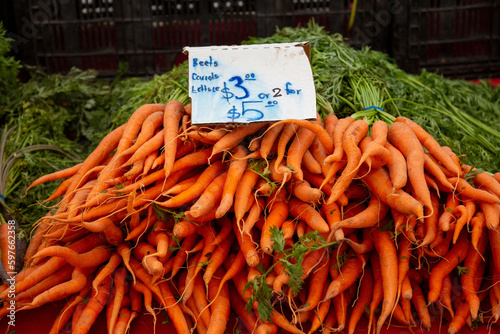 Pile of orange carrots at farmers market with price sign handwritten