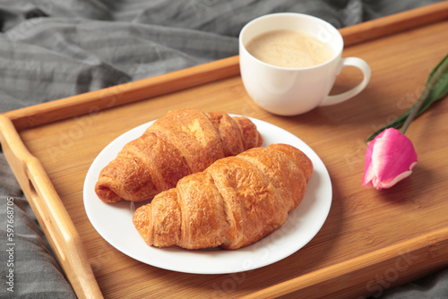 Breakfast in bed with coffee, croissants and tulip on tray