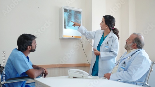 Woman medical assistant talking and explaining the X-ray results of the patient s body and there was an old male doctor sitting there listening at hospital