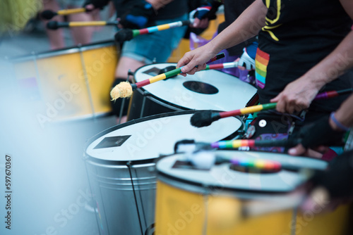 Colorful drum band playing drums in the street at a public event during Pride festival in June.