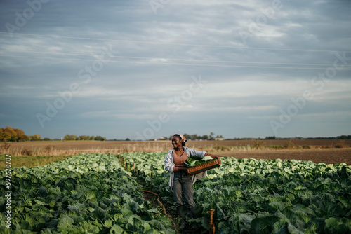 African American farm female worker harvesting raw veggies on the farm. Copy space