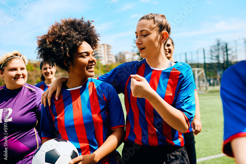 Black soccer player and her teammates talk after practice on stadium.