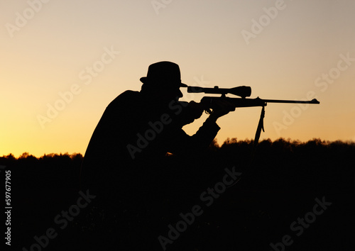 Hunting, sunset, man with gun and focus on target in nature to hunt game for sport on safari adventure. Sky, silhouette and hunter with rifle in bush, setting sun and shooting hobby on summer evening