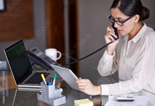 Telephone, tablet and businesswoman on a call in the office doing research on the internet. Technology, landline and professional female employee working on corporate project with mobile in workplace photo