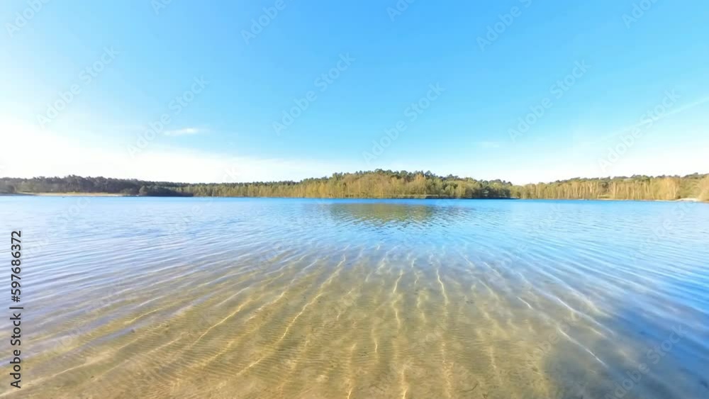 idyllischer See mit kristallklarem Wasser,, kleinen Wellen,  Sonnenschein blauer Himmel, Drohne