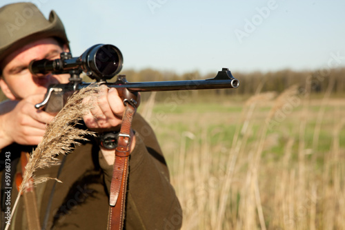Hunting, gun and man on a Africa safari in the grass for shooting animals on holiday. Weapon, sniper and male person aim for wild game in nature with mockup and scope for target shot in the sun