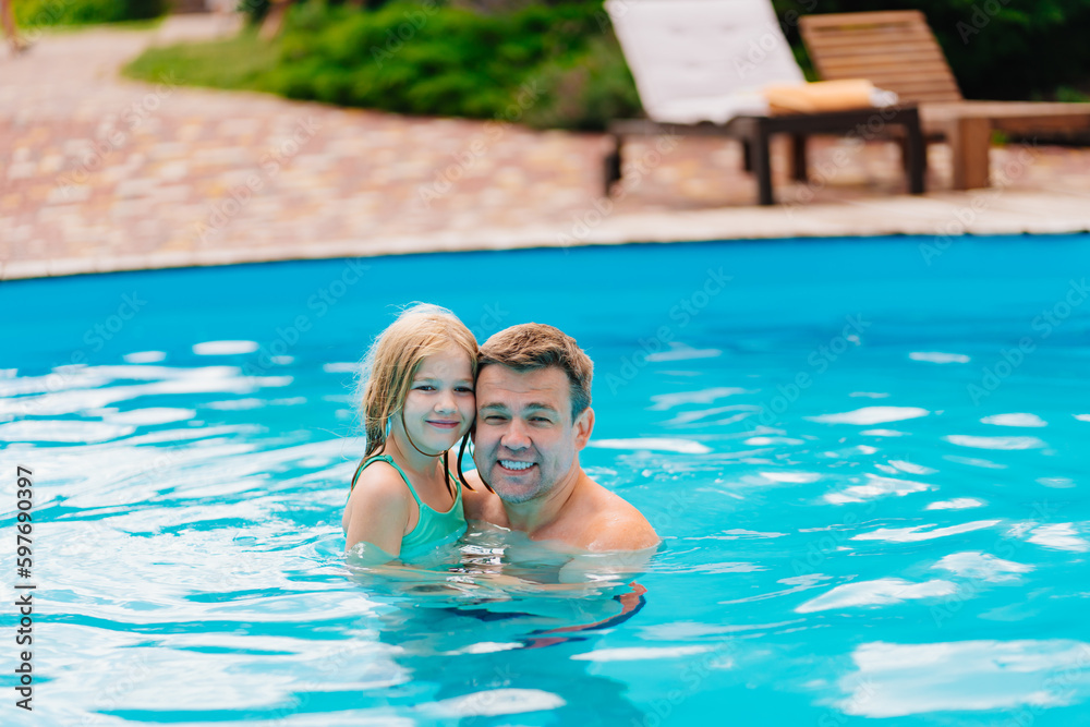 Dad and daughter play in the pool. dad hugs his daughter
