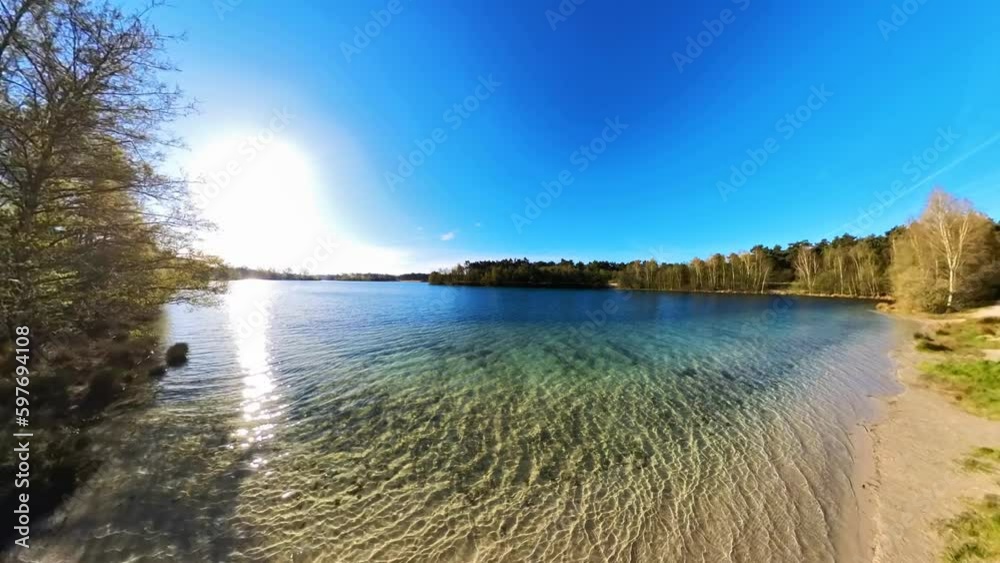idyllischer See mit kristallklarem Wasser,, kleinen Wellen,  Sonnenschein blauer Himmel, Drohne