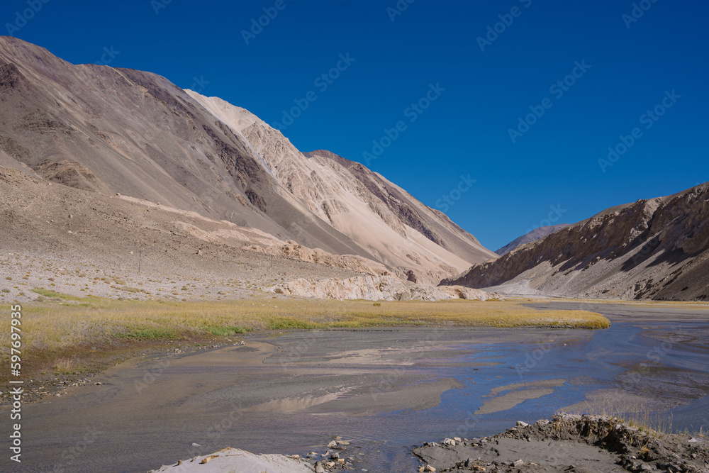 grassland, small river and mountain, blue sky at Ladakh, India