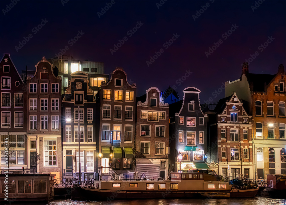 Obraz premium Typical Houses by the River Amstel in the Central Part of Amsterdam, at Night
