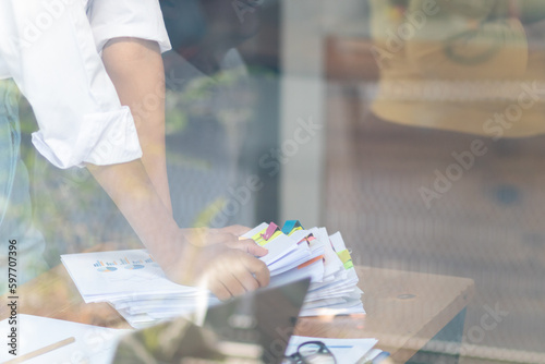 Businesswoman hands working on stacks of paper documents to search and review documents piled on table before sending them to board of directors to use  correct documents in meeting with Businessman