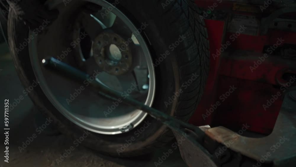 closeup of male hand changing tire on wheel in workshop closeup of male hand changing tire on wheel in workshop