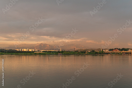 A mountain that looks like a golden color by the clouds behind the lake at sunset. And that reflection