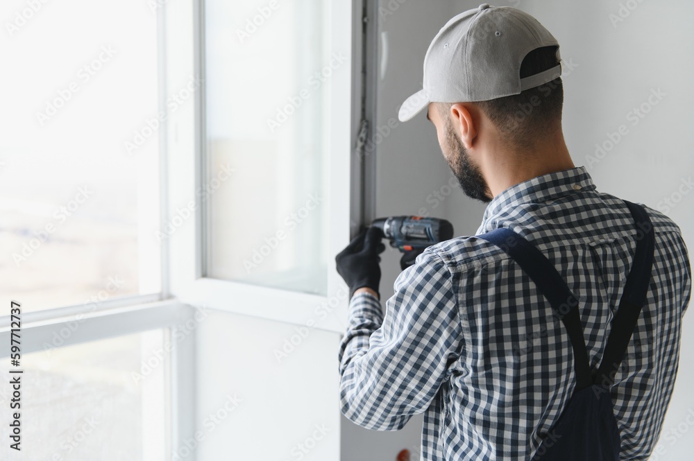 Construction worker installing window in house Construction worker installing window in house