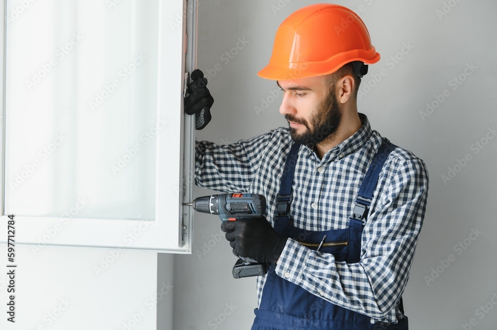 Construction worker installing window in house Construction worker installing window in house