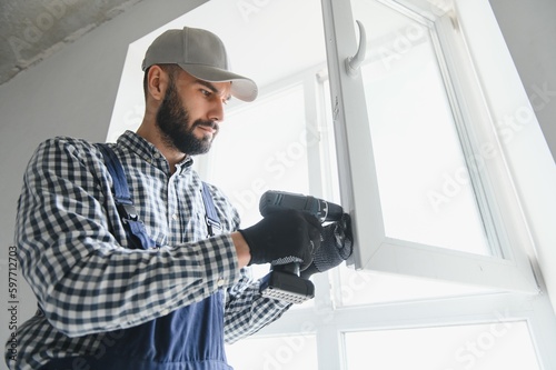 Worker installing plastic window indoors