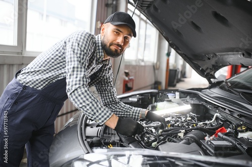 Adult man in blue colored uniform works in the automobile salon.