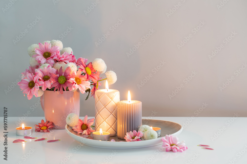 burning candles and pink and white  chrysanthemums in white interior