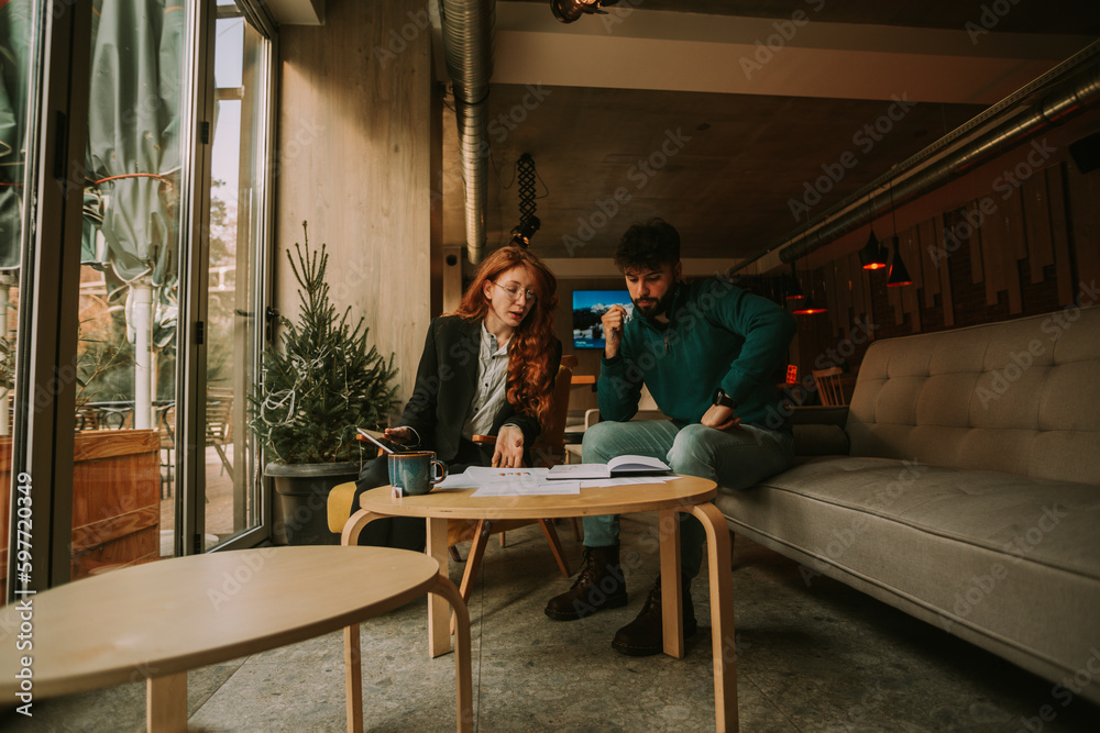 Low angle view photo of two Caucasian business people, male and female, creating new marketing strategy while working together at the coffee bar