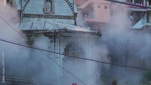 Closeup shot of Shiva temple besides the Paravati river at Manikaran in Himachal Pradesh, India. Steam from hot springs near the temple in front of temple. Shiva temple at Manikaran in winter.  photo