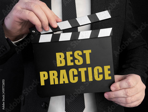 A businessman holds up a ?lapperboard with text Best Practice photo